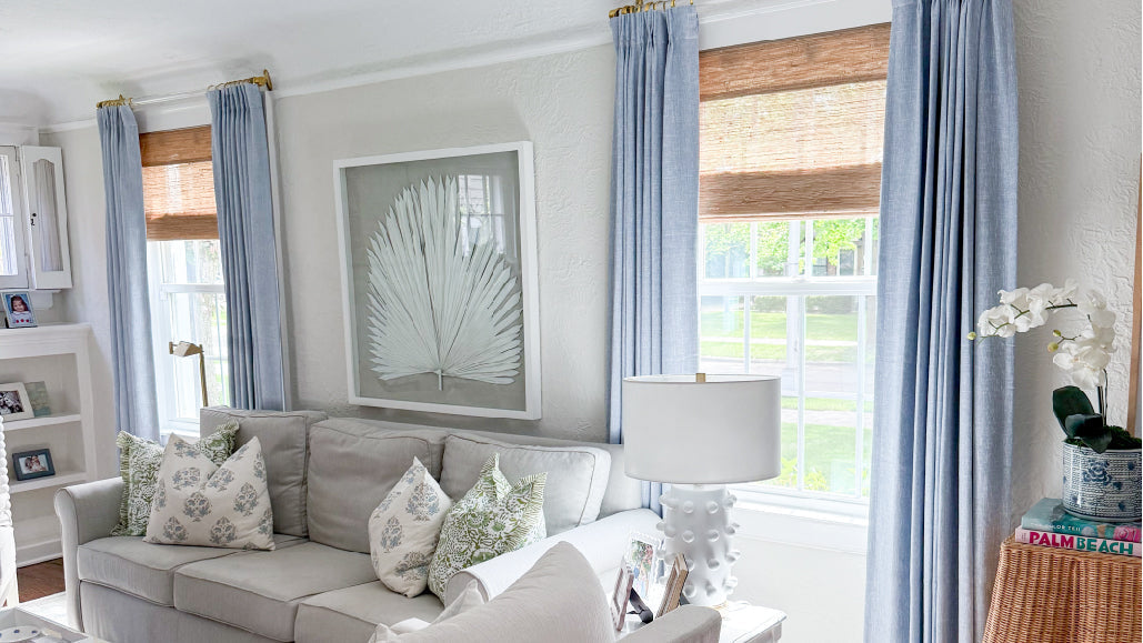 Bright living room space featuring light blue drapery, bamboo blinds, and a gray sofa.