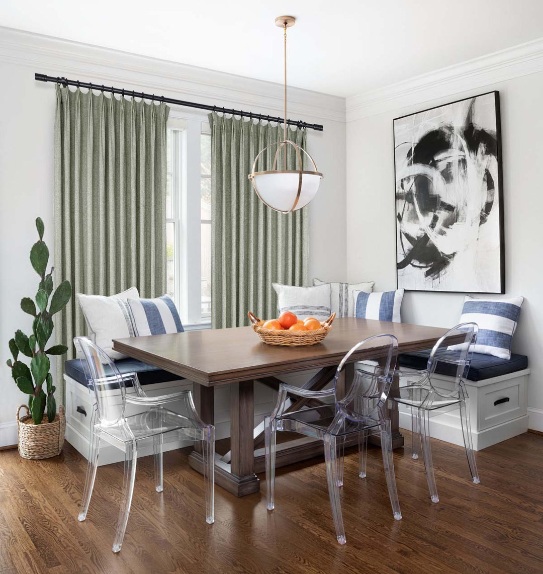 Modern dining nook featuring sage green pleated curtains, a wooden table, built-in bench seating, and acrylic chairs.
