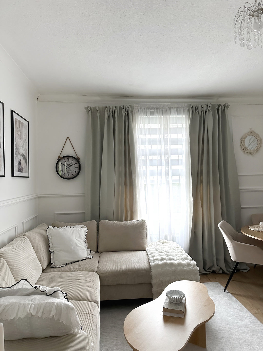 Cozy living room featuring a beige sectional sofa, layered grey and sheer curtains, and a modern wooden coffee table.