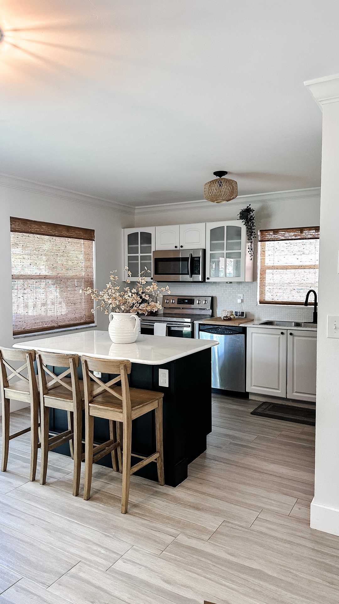 Modern kitchen featuring natural bamboo woven Roman shades, white cabinets, and a center island.