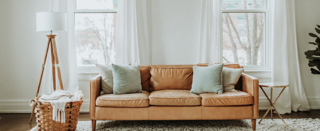 LUSTROWIN luxury floor-length white linen drapes framing twin windows in a bright boho minimalist living room with a tan leather sofa and warm accents.