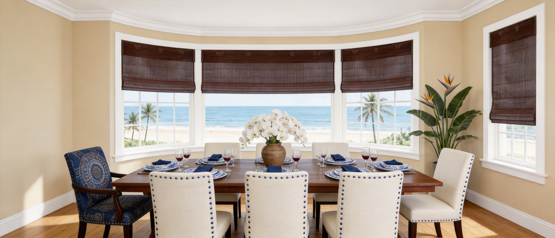 Coastal dining room bay window featuring dark woven shades and an elegant dining table set.
