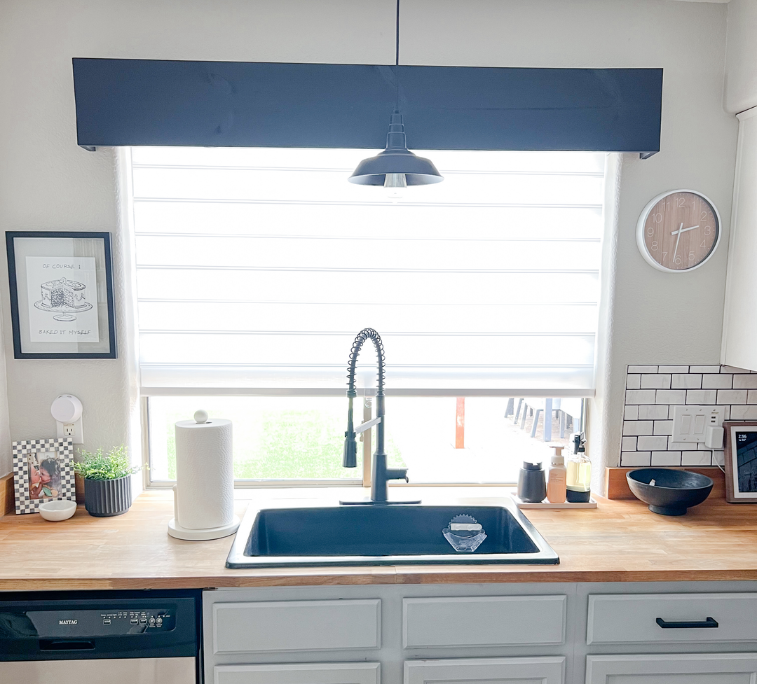 Bright modern kitchen sink area featuring a wooden countertop, black faucet, and a window with white zebra shades.